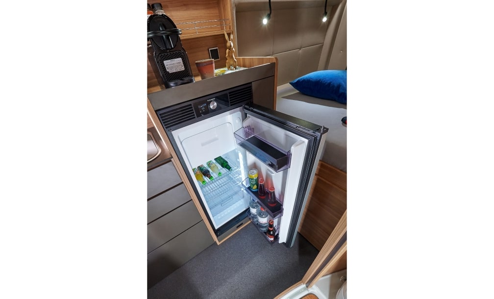 Geöffneter Kühlschrank mit Blick auf die Kaffeemaschine im Wohnbereich