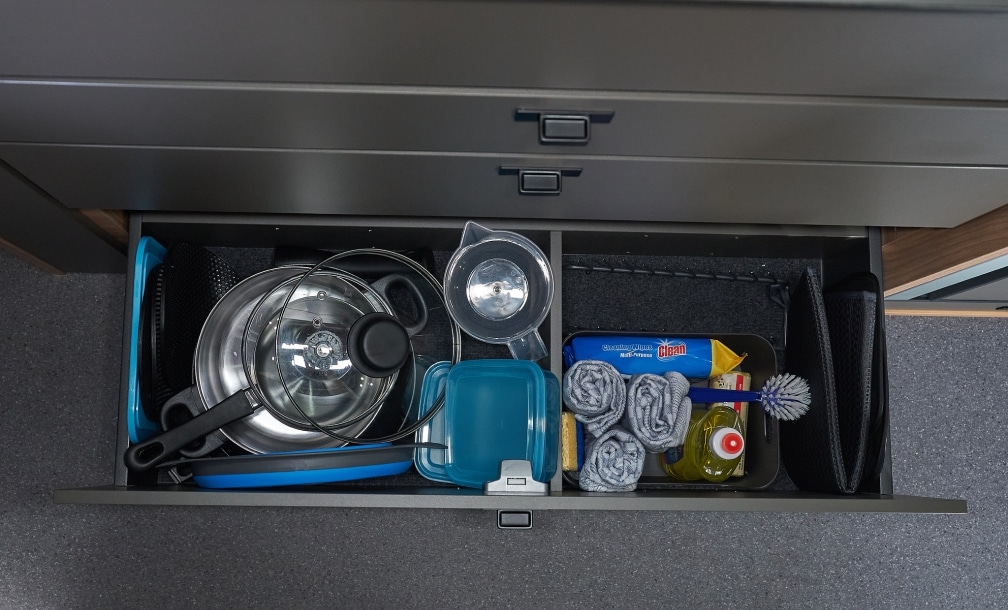 Geöffnete Schublade mit Topfset und Campingzubehör in der Vollküche