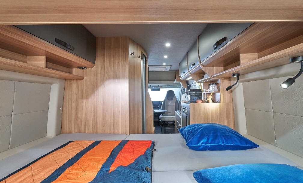 Wohnraum mit Bett, Spiegel und Holzverkleidung im Peugeot Boxer Campervan
